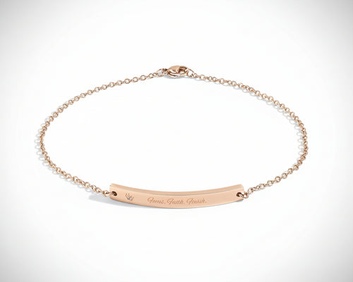 Rose gold bracelet with engraved text on a white background